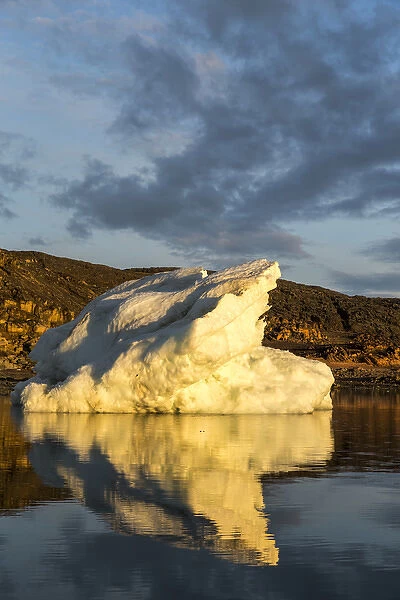 Canada, Nunavut Territory, Midnight sun lights melting iceberg reflected in Frozen