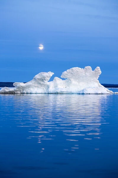 Canada, Nunavut Territory, Moon rises behind melting iceberg in Frozen Channel at