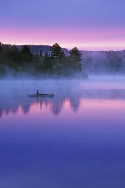 Canada, Ontario, Algonguin Park, Canoeist on lake at sunrise. Credit as: Nancy Rotenberg