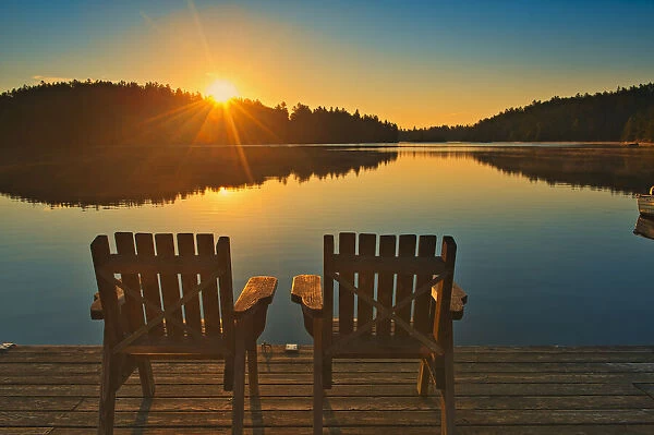 Canada, Ontario, Temagami. Muskoka chairs on Snake Island Lake dock at sunrise