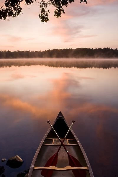 A canoe rests on the shore of Pawtuckaway Lake at dawn as seen from Horse Island