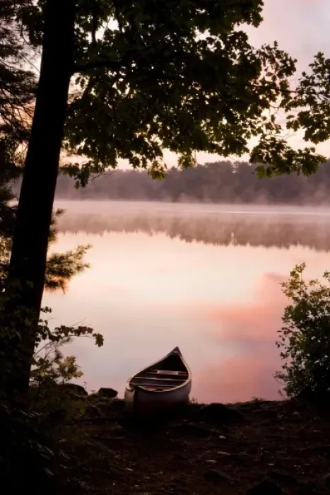 Framed Print : A canoe rests on the shore of Pawtuckaway Lake at dawn as seen from Horse Island