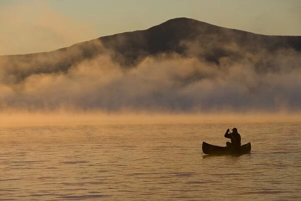 Canoeing in Lily Bay at sunrise, Moosehead Lake, Maine. Lily Bay Mountian is in the distance