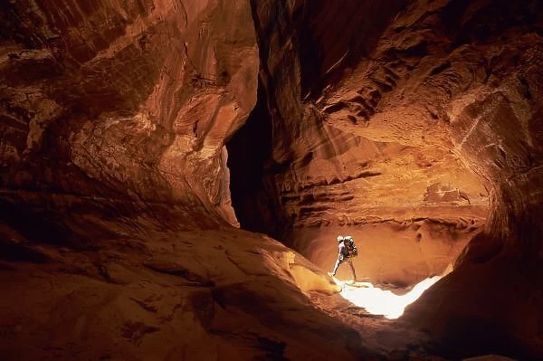Canyoneer illuminated in the depths of a narrow canyon in the Dirty Devil Canyon