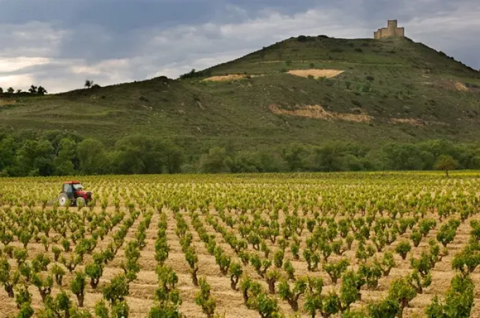 Framed Print : Castle towers over tractor working vineyards along the San Vicente to Banos de Ebro