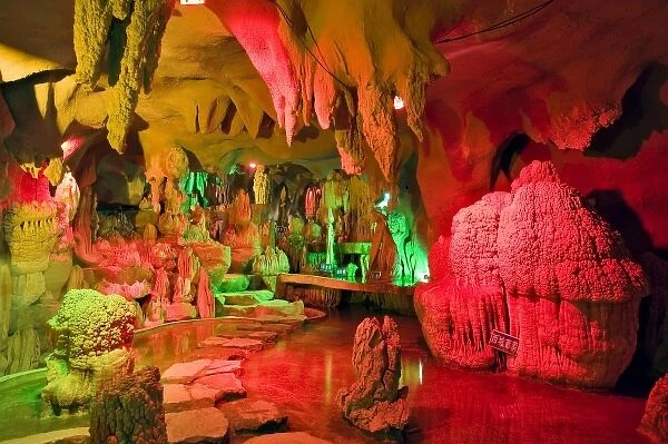 A cave of stalagmites and stalactites lighted with colored lights near the entrance