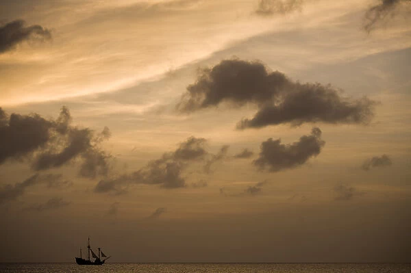 Cayman Islands, Grand Cayman Island, Setting sun silhouettes yacht sailing through