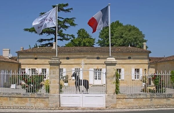Chateau La Couspaude, the main building, with a white iron fence a French flag