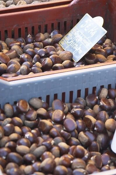 Chestnuts for sale at a market stall at the market in Bergerac in a red and grey plastic basket