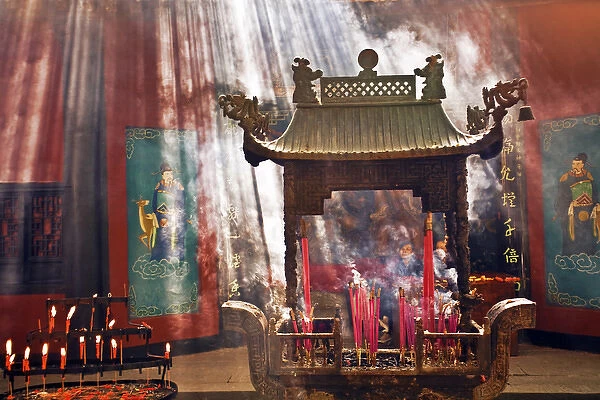 China, Hangzhou, Lingyin Buddhist Temple candles and incense burn at an alter as buddists pray