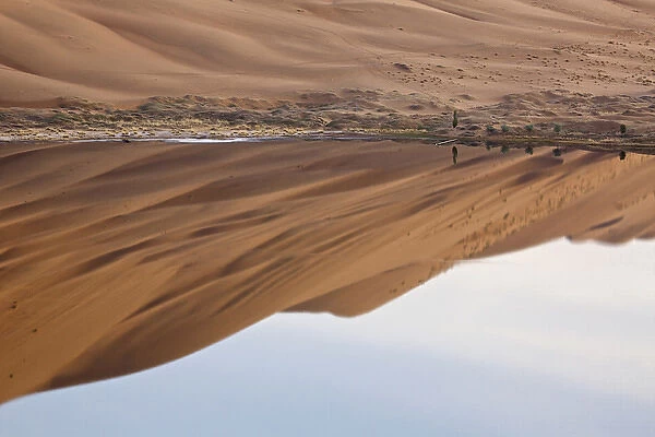 China, Inner Mongolia, Badan Jilin Desert. Desert and sky reflected in lake. Credit as