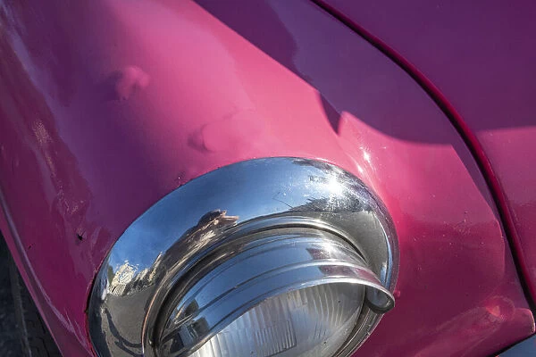 Detail of chrome head light on hot pink classic American Oldsmobile in Vieja, old Habana