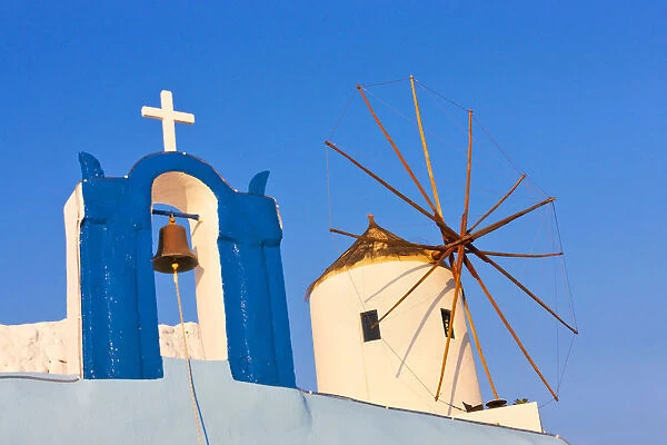 Church bell tower and windmill on the coast of Aegean Sea. Oia, Santorini Island, Greece
