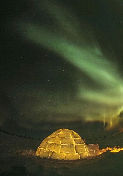 Churchill, Manitoba, Canada. Northern Lights shine above lit igloo