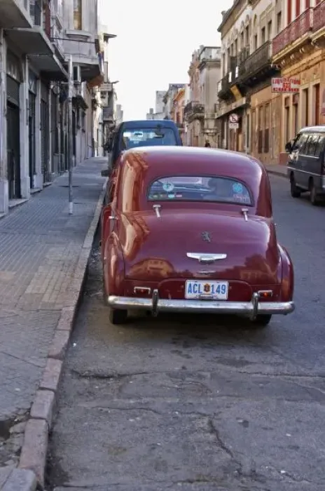 Framed Print : A classic old red Peugeot car parked on a street corner, probably from the 1950s