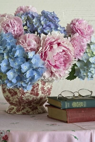 Close-up of hydrangea and peony flower arrangement on table next to books