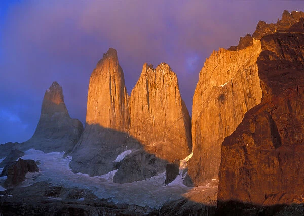 Clouds swirl around the sunrise-colored rocky points of Cerro del Torres in Patagonia