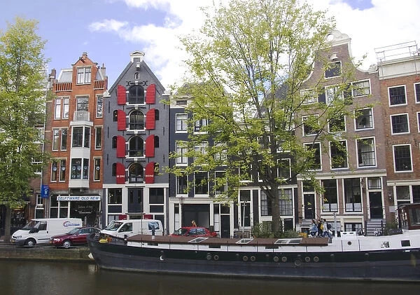 Colorfu buildings line an Amsterdam canal with a houseboat parked out front