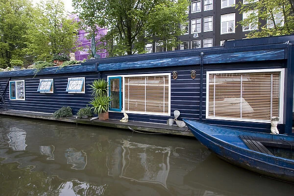 a colorful blue houseboat with matching row boat on a canal