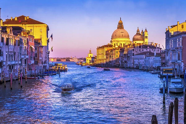 Colorful Grand Canal and Santa Maria della Salute church under sunset with reflection in