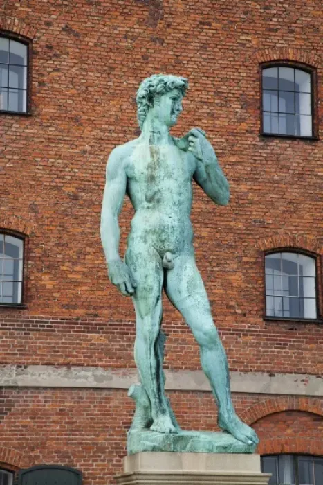 Framed Print : Copenhagen, Denmark - Low angle view of a sculpture of David. A brick building is
