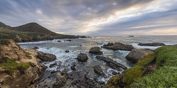 Cove of rocks and waves along Big Sur coastline with stormy skies