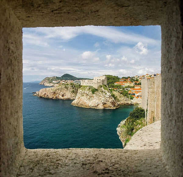 Croatia, Dubrovnik. Ancient fortress on the cliff edge of Dubrovnik protects the port as seen from through a window on the wall surrounding the city