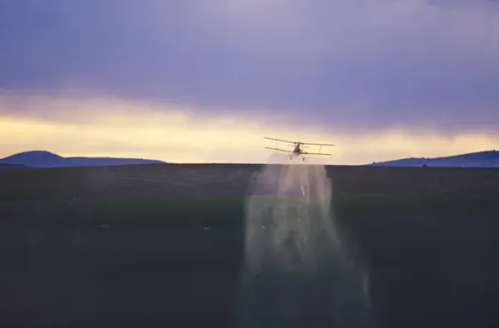 Framed Print : Crop duster airplane applies chemicals to wheat crop at sunset near Kendrick Idaho
