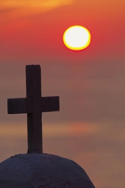Cross on church at sunset over ocean, Mykonos, Greece