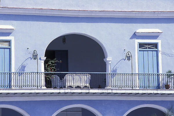 Cuba, Havana. Balcony of blue building with white wicker furniture in archway. Credit as