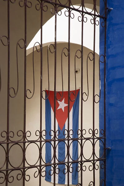 Cuba, Vinales, Cuban flag in courtyard and wrought iron gate