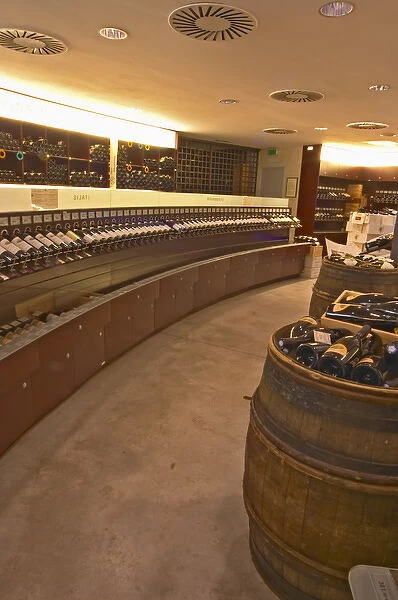A curved display of bottles and a barrel used to present bottles The Lavinia wine shop in Paris