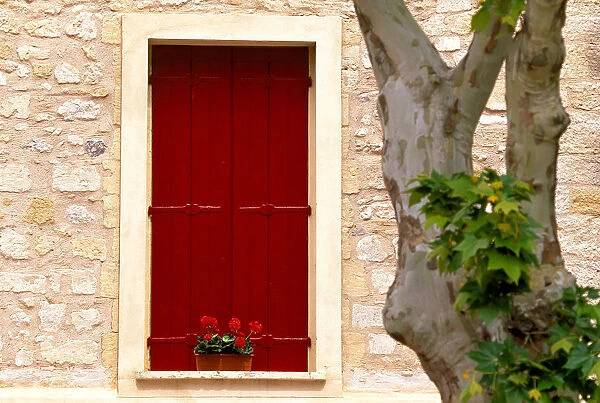 Dark red shutters in the wall of a house in France