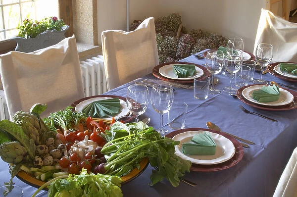 The dining room table decorated and set with flowers and decorative vegetables for dinner guests