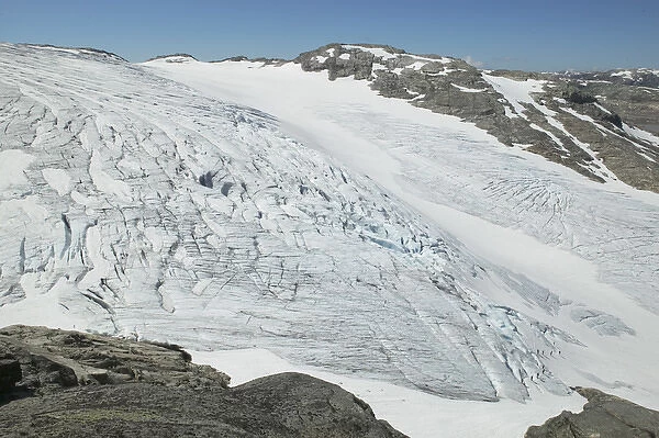distant Glacier hikers wind through the blue ice crevices and over snow fields of