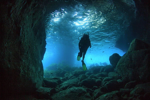 Diver swimming through a sea cave near Poor Knights Islands, North Island, New Zealand