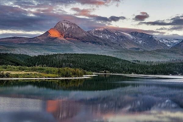 Divide Mountain catches alpenglow light at sunset over St. Mary Lake in Glacier National Park, Montana, USA