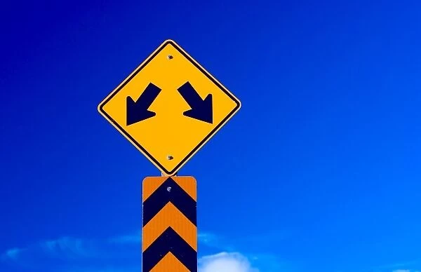 a double arrow traffic sign with a blue sky behind