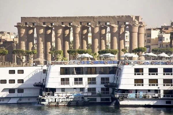 Egypt, Luxor. Nile cruise boats docked side by side and the gigantic columns of Luxor