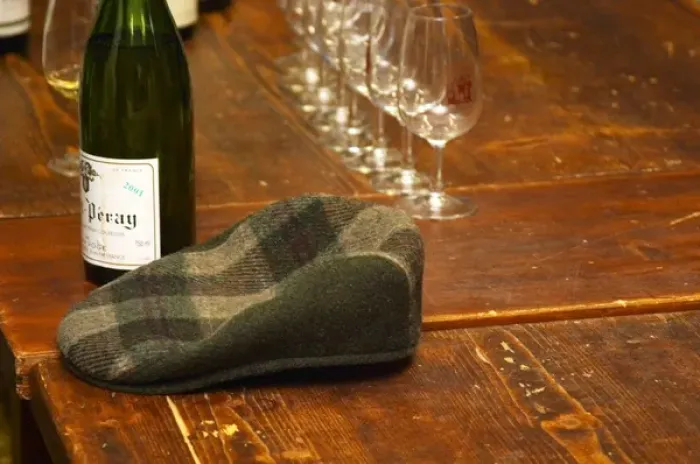 Framed Print : The emblematic cap of Alain Voge on a wooden table and some wine glasses and bottles