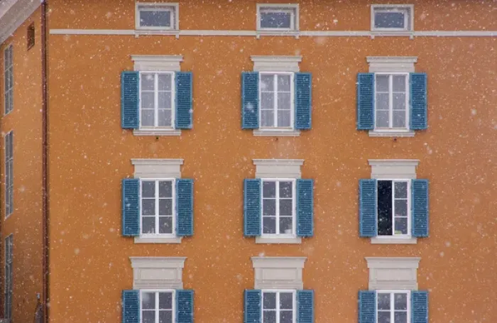 Framed Print : Europe, Austria, Salzburg. Blue shutters on orange apartment building in snowfall