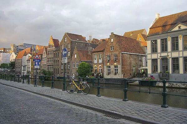 Europe, Belgium, Ghent. A bicycle parked on a paved-stone sidewalk by the water