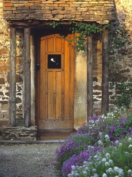 Europe, England, Chippenham. An old wooden door welcomes visitors to a thatched-roofed