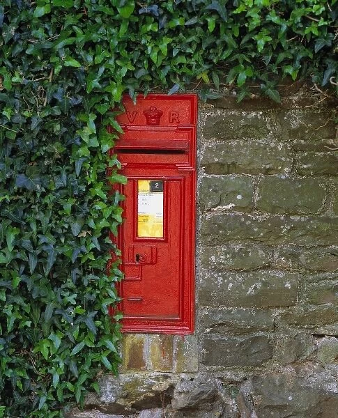 Europe, England, Dorset. A bright red post-box adorns this stone wall in Dorset in southern England