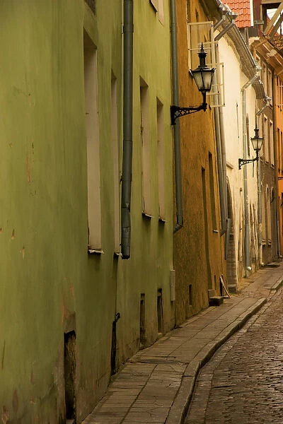 Europe, Estonia, Tallinn. Narrow cobblestone street with lamps on buildings. Credit as