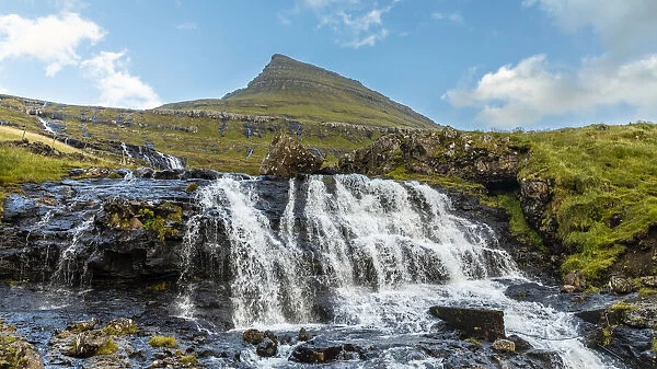 Europe, Faroe Islands. View of waterfall cascading down a hillside in the Faroe Islands