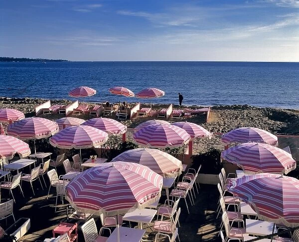 Europe, France, Cannes. Pink stripped umbrellas stand ready for visitors on the beach