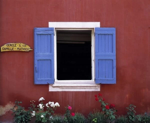 Europe, France, Roussillon. Blue shutters frame an open window in the colorful village
