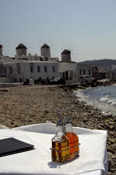 Europe, Greece, Mykonos. Waterfront cafe, historic windmills in distance