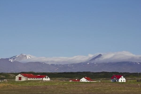 Europe, Iceland, West Fjords, scenic landscape of barn and houses in foreground against mountains